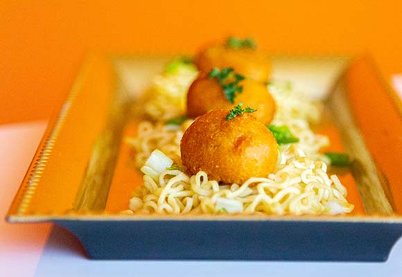 Mini corn dogs and ramen Three mini corn dogs on top of small beds ramen noodles